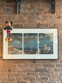 a mickey mouse stuffed animal sits on top of a brick wall