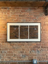 three framed prints hanging on a brick wall
