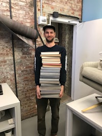 a man standing in front of a stack of books