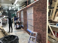 a man is working on a brick wall in a workshop